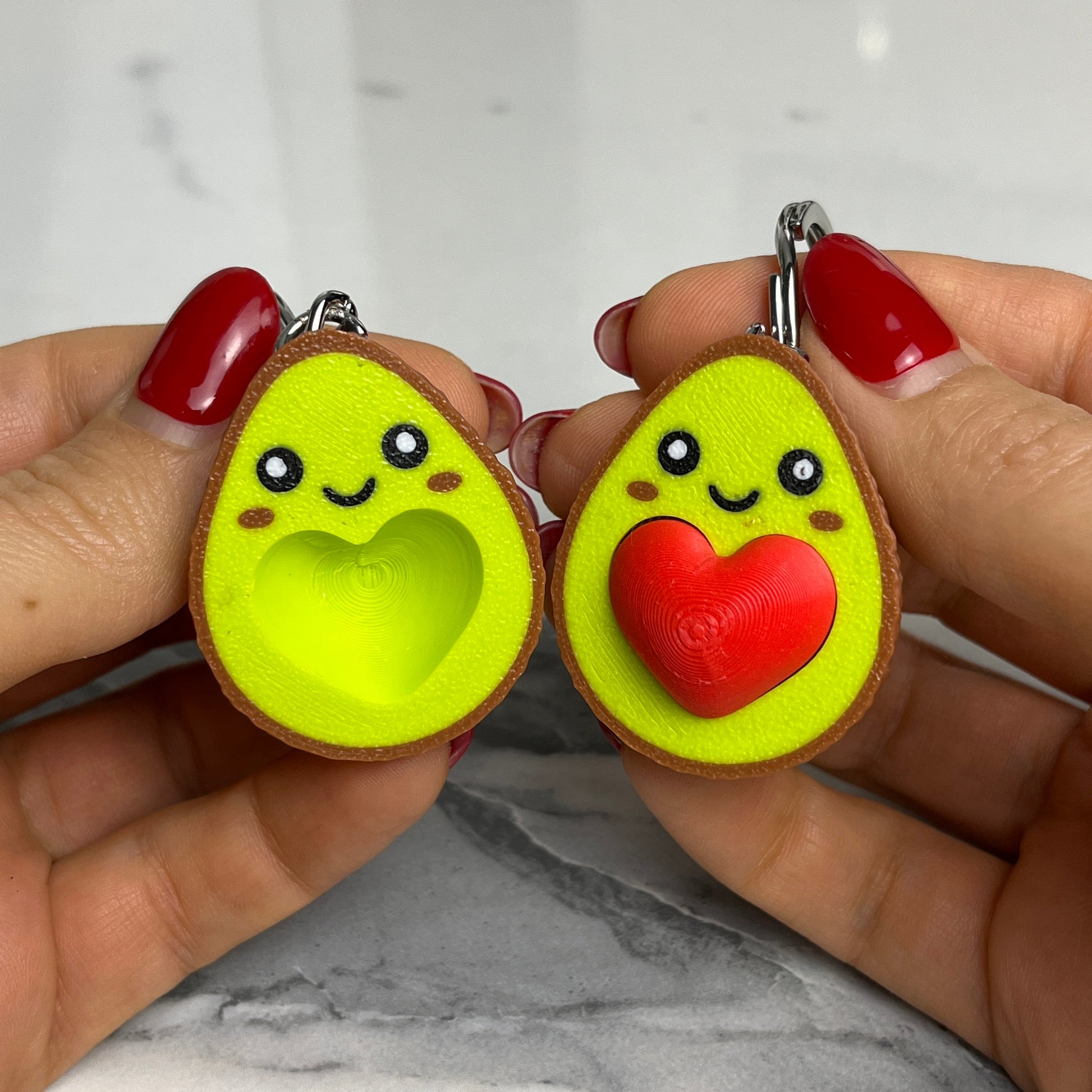 Two magnetic avocado shaped key chains with faces and one with a heart