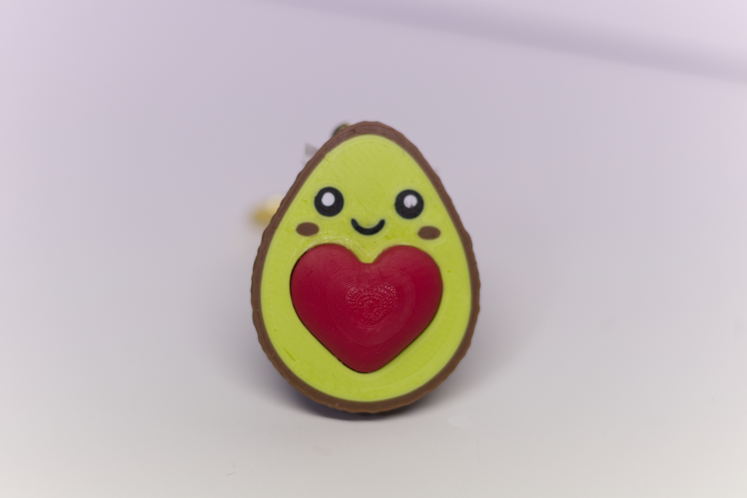 Half of the pair of avocado key chain with a heart attached